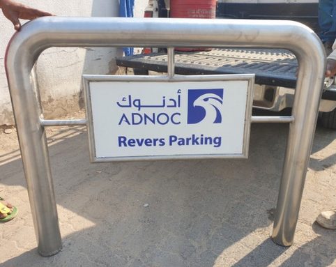 Steel guard rail carrying an ADNOC parking sign